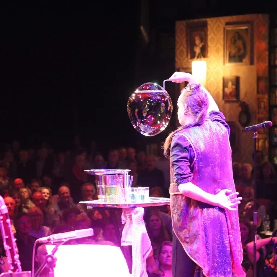 Magische bellenblaas show op bedrijfsevenement Iemand creëert een grote zeepbel op een podium voor een publiek.
