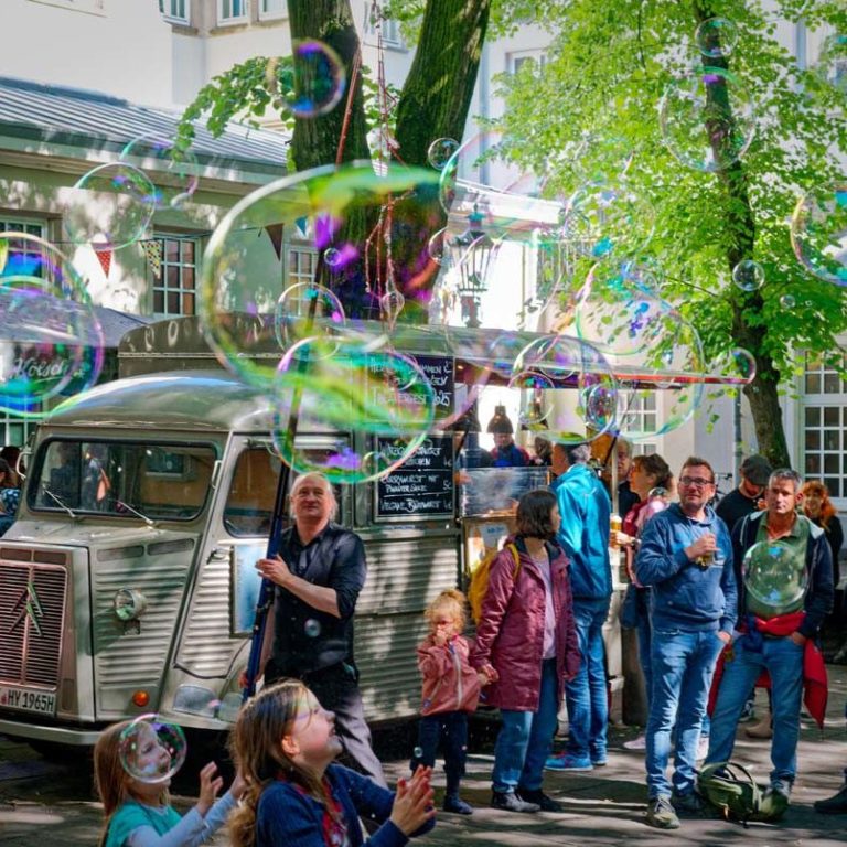 Bellenblaas artiest in actie met reuze zeepbellen walk-act – bubble show buiten in Vlaanderen