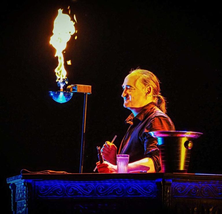 Een glimlachende circusartiest staat naast een brandende zeepbel.